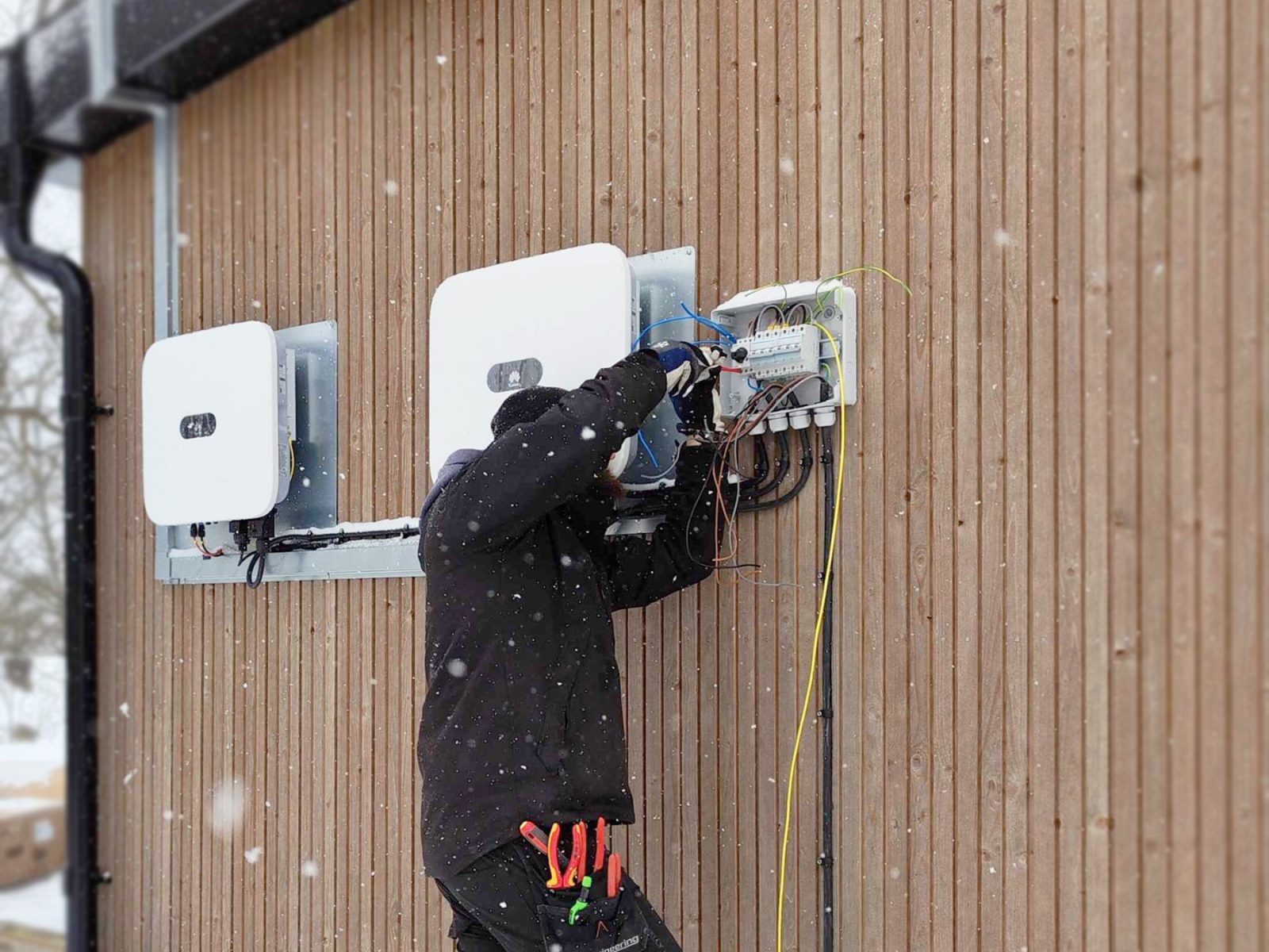 Eltekniker installerar solpanelväxelriktare på trävägg
